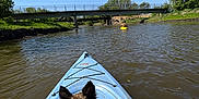 Rose is registered to the contest to win money with this photo: adventure, animal, blue_sky, bridge, calm, canal, dog, greenery, kayak, leisure, nature, outdoor, paddling, person, pet, recreation, river, summer, sunny, water