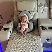 Roma is registered to the contest to win money with this photo: baby, infant, baby_seat, recliner, leather_furniture, living_room, speaker, quilted_pattern, head_support, footrest, carpet, phone, remote_control, neutral_expression, indoor, modern_furniture, technology, comfort, seat_cushion, blue_light