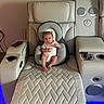 baby, infant, baby_seat, recliner, leather_furniture, living_room, speaker, quilted_pattern, head_support, footrest, carpet, phone, remote_control, neutral_expression, indoor, modern_furniture, technology, comfort, seat_cushion, blue_light
