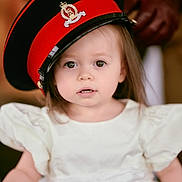 Iris joined the competition — help win amazing prizes! toddler, child, hat, military_hat, white_dress, portrait, face, curious, indoor, person, cute, young_child, fashion, costume, apparel, headwear, expression, closeup, soft_lighting, blurry_background