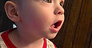 Harold is registered to the contest to win money with this photo: child, clothing, cute, ear, expression, eyes, face, head, indoor, light, mickey_mouse, mouth_open, person, portrait, shirt, sitting, skin, toddler, wooden_background, young