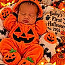 baby, newborn, sleeping, halloween, pumpkin_costume, orange, jack_o_lantern, ghost, plush_toys, blanket, portrait, infant, costume, festive, cozy, indoor, decorations, wooden_sign, photography, cute