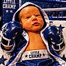 athlete, baby, blanket, blue, boxing, boxing_gloves, boxing_ring, champion, child, costume, dramatic_lighting, face, indoors, infant, photography, portrait, robe, seated, sports, stars