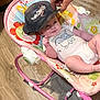 baby, infant, baby_rocker, onesie, dumbo, hand, tattoo, cap, pink, floor, wooden_floor, indoor, smile, cute, child, playful, person, clothing, baby_toys, baby_seat