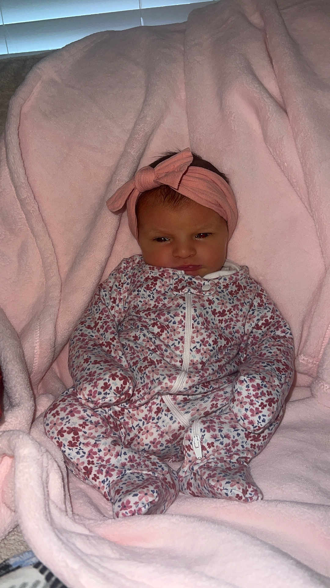 Amya is registered to the contest to win money with this photo: baby, child, infant, blanket, pink, headband, bow, onesie, floral_pattern, clothing, cozy, soft, cute, face, portrait, sitting, indoors, warm, newborn, cute_expression