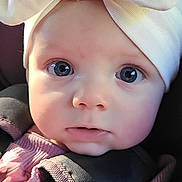 Adaley is registered to the contest to win money with this photo: baby, blue_eyes, bow, car_seat, child, closeup, cute, expression, face, hands, headwear, indoors, infant, person, portrait, purple_clothing, seatbelt, skin, soft_lighting, young_child