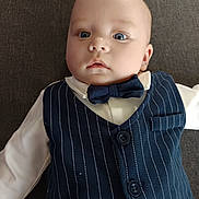 Lylio participe au concours pour gagner de l'argent avec cette photo : baby, infant, child, face, blue_eyes, bow_tie, vest, pinstripe, white_shirt, clothing, portrait, lying_down, cute, young, person, indoors, fashion, formal, expression, head