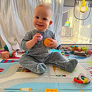 Lenny a rejoint le concours — aidez-le/la à gagner de superbes lots ! baby, child, colorful, cute, daylight, face, floor, footwear, hands, happy, indoor, infant, pajamas, plastic_toys, playmat, playpen, room, sitting, smiling, toys