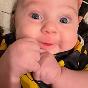 Kingston is registered to the contest to win money with this photo: baby, infant, face, hands, eyes, chubby_cheeks, clothing, black, yellow, blanket, furniture, indoor, portrait, closeup, cute, person, skin, expression, child, newborn