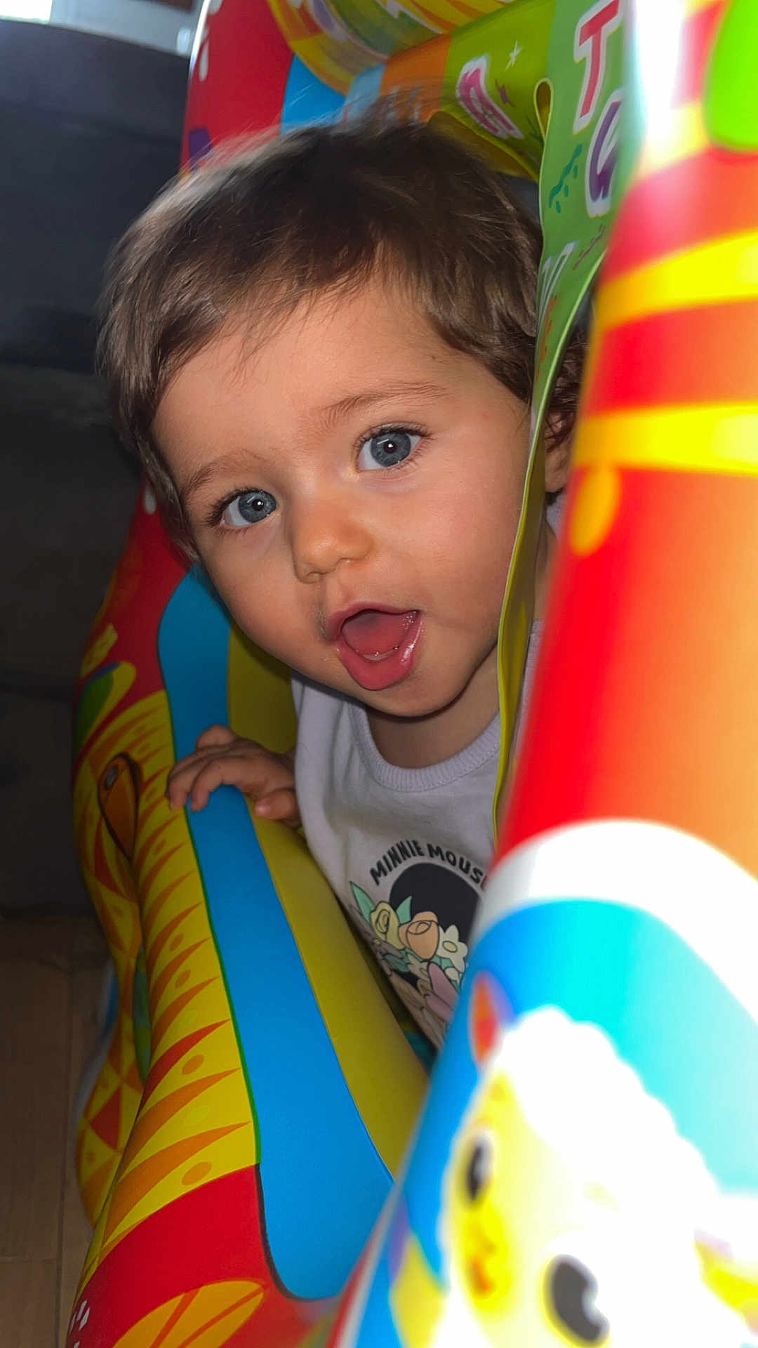 Mila a rejoint le concours — aidez-le/la à gagner de superbes lots ! toddler, child, face, blue_eyes, mouth_open, inflatable_toy, colorful, indoor, playful, happy, curly_hair, clothing, minnie_mouse, toy, bright_colors, closeup, person, young_child, expression, fun