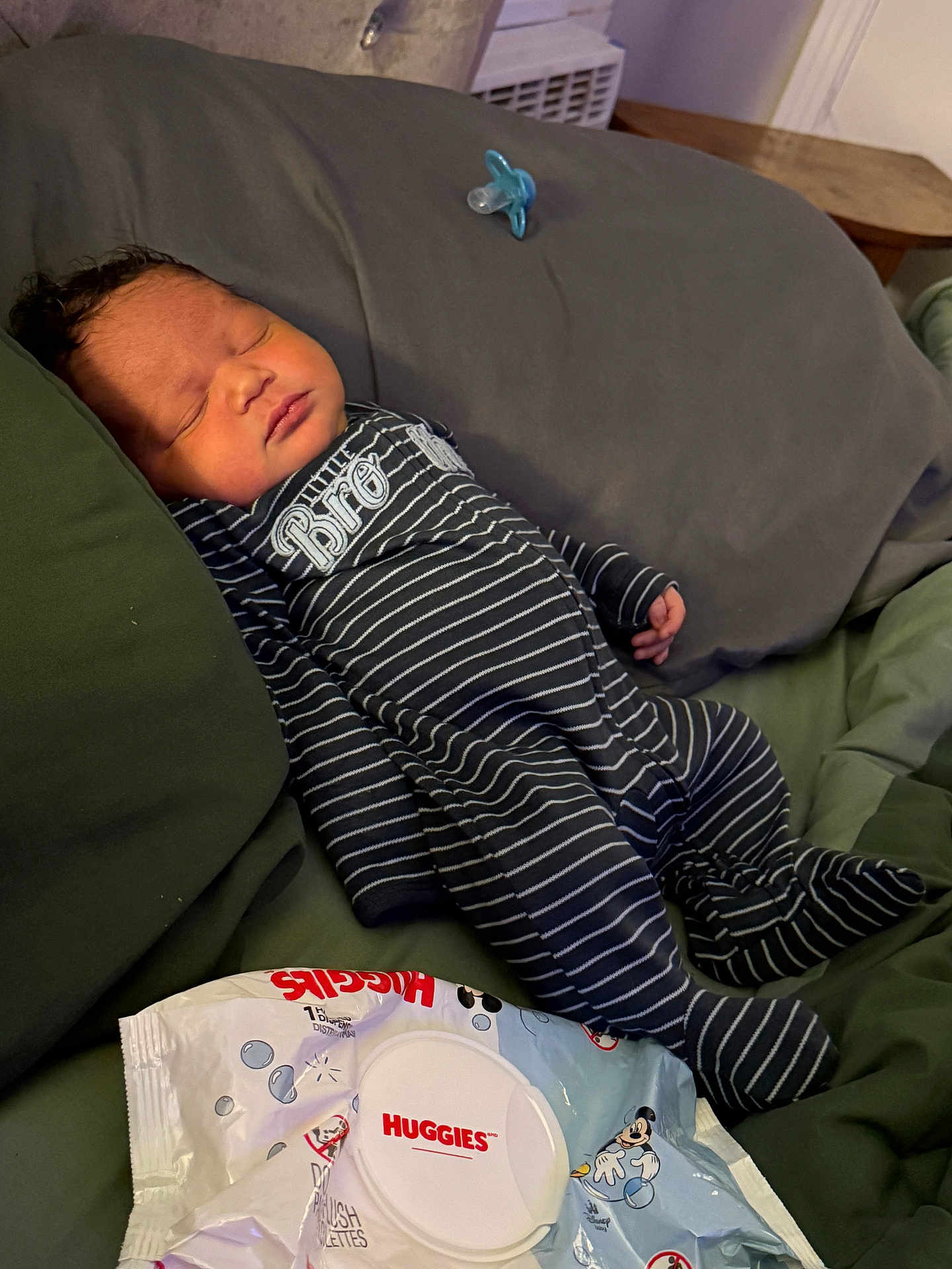 Lenoxx is registered to the contest to win money with this photo: baby, newborn, sleeping, onesie, striped_clothing, pacifier, huggies_wipes, bed, pillow, infant, child, resting, cute, indoor, soft_lighting, peaceful, toddler, person, young_child, cozy