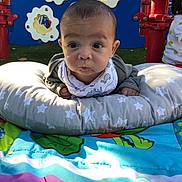 Elias is registered to the contest to win money with this photo: baby, child, outdoor, playground, pillow, colorful, curious_expression, clothing, play_mat, face, person, toddler, green, blue, red, yellow, fabric, head, smile, infant