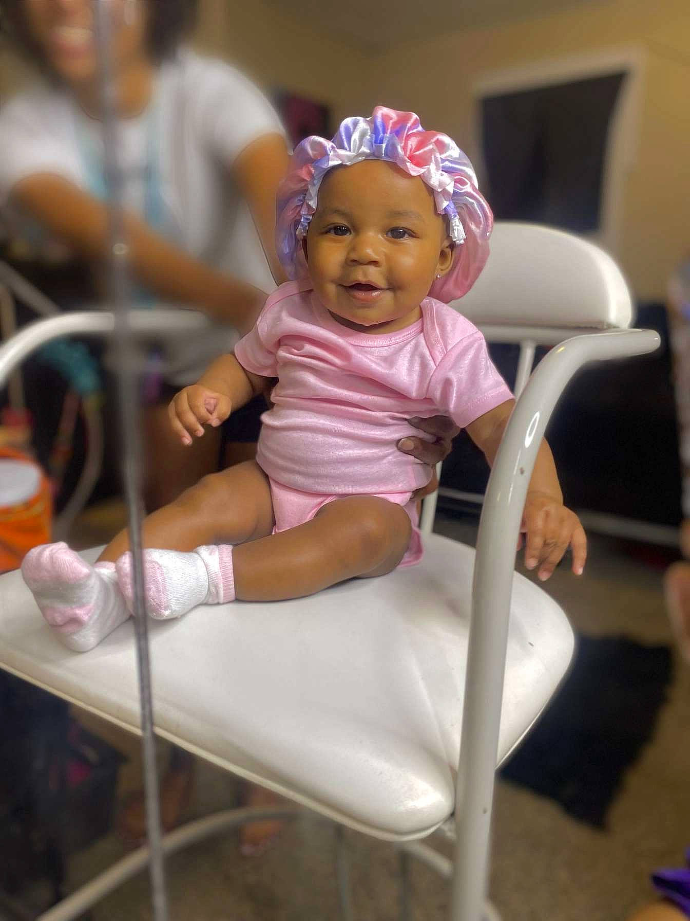 Azuri is registered to the contest to win money with this photo: baby, baby_products, baby_toddler_clothing, chair, child, comfort, event, fun, happy, hat, headgear, headwear, human_leg, magenta, person, purple, room, sandal, sitting, smile