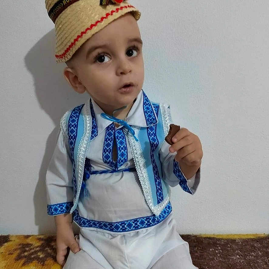 Patrick is registered to the contest to win money with this photo: accessories, baby, bodypart, bonnet, cap, clothing, coat, costume, face, finger, formalwear, hand, hat, head, pants, person, photography, portrait, tie, toy