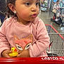 child, clothing, costco, curious, cute, expression, fox_design, holding, indoor, panda_earrings, people, pink_sweater, portrait, retail, shopping, shopping_cart, store, supermarket, toddler, yellow_rubber_duck