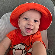 Thaddeus is registered to the contest to win money with this photo: baby, baby_boy, baby_girl, bucket_hat, cartoon, child, clothing, cushion, cute, face, happy, indoor, orange_hat, orange_shirt, person, portrait, seat, smiling, tigger, young_child