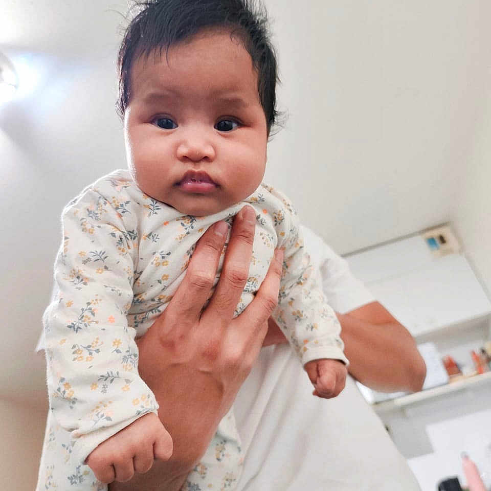 Riantsoa a rejoint le concours — aidez-le/la à gagner de superbes lots ! baby, infant, child, hand, adult, person, indoor, kitchen, clothing, onesie, face, hair, expression, holding, portrait, cute, young, skin, fingers, light