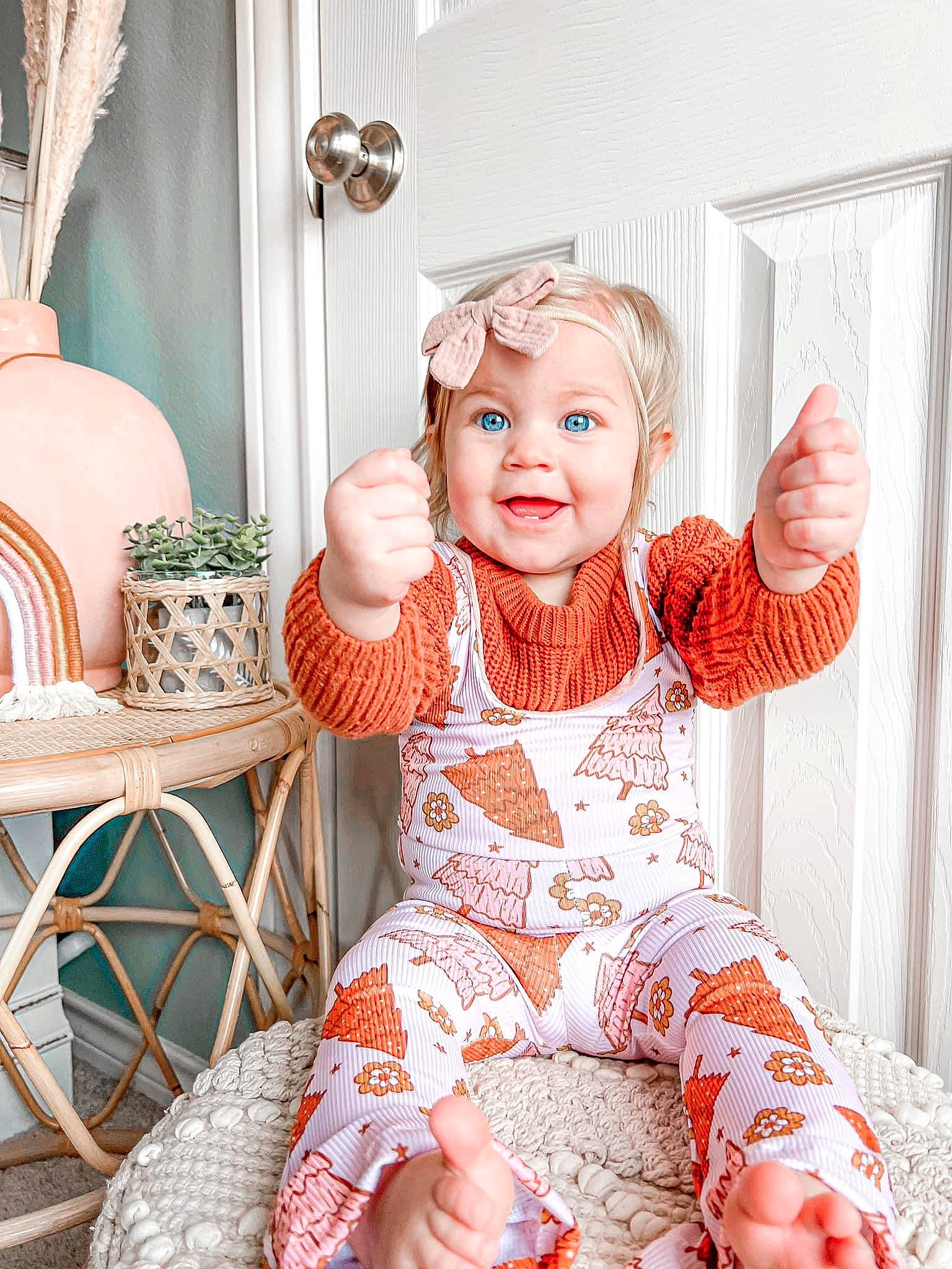 Kinley is registered to the contest to win money with this photo: baby_toddler_clothing, child, comfort, curtain, happy, headwear, human_leg, leg, orange, pattern, peach, person, picture_frame, pink, sitting, sleeve, smile, sock, textile, thigh