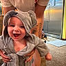 Hendrick is registered to the contest to win money with this photo: adult, baby, carpet, child, clothing, cute, happy, holding, home, hood, indoor, kitchen, koala, person, playful, refrigerator, robe, smile, tattoo, toddler