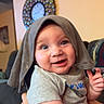 Hendrick is registered to the contest to win money with this photo: arm, baby, blue_eyes, child, clothing, couch, cute, decor, fabric, face, hand, happy, indoor, infant, living_room, person, playful, portrait, smiling, wall_clock