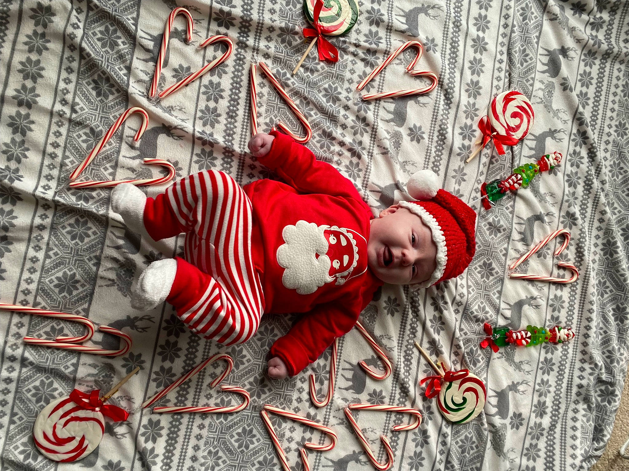 Lennox is registered to the contest to win money with this photo: art, baby, baby_toddler_clothing, carmine, child, christmas_decoration, christmas_eve, christmas_ornament, event, flooring, font, happy, hat, headwear, holiday, pattern, person, sleeve, smile, textile