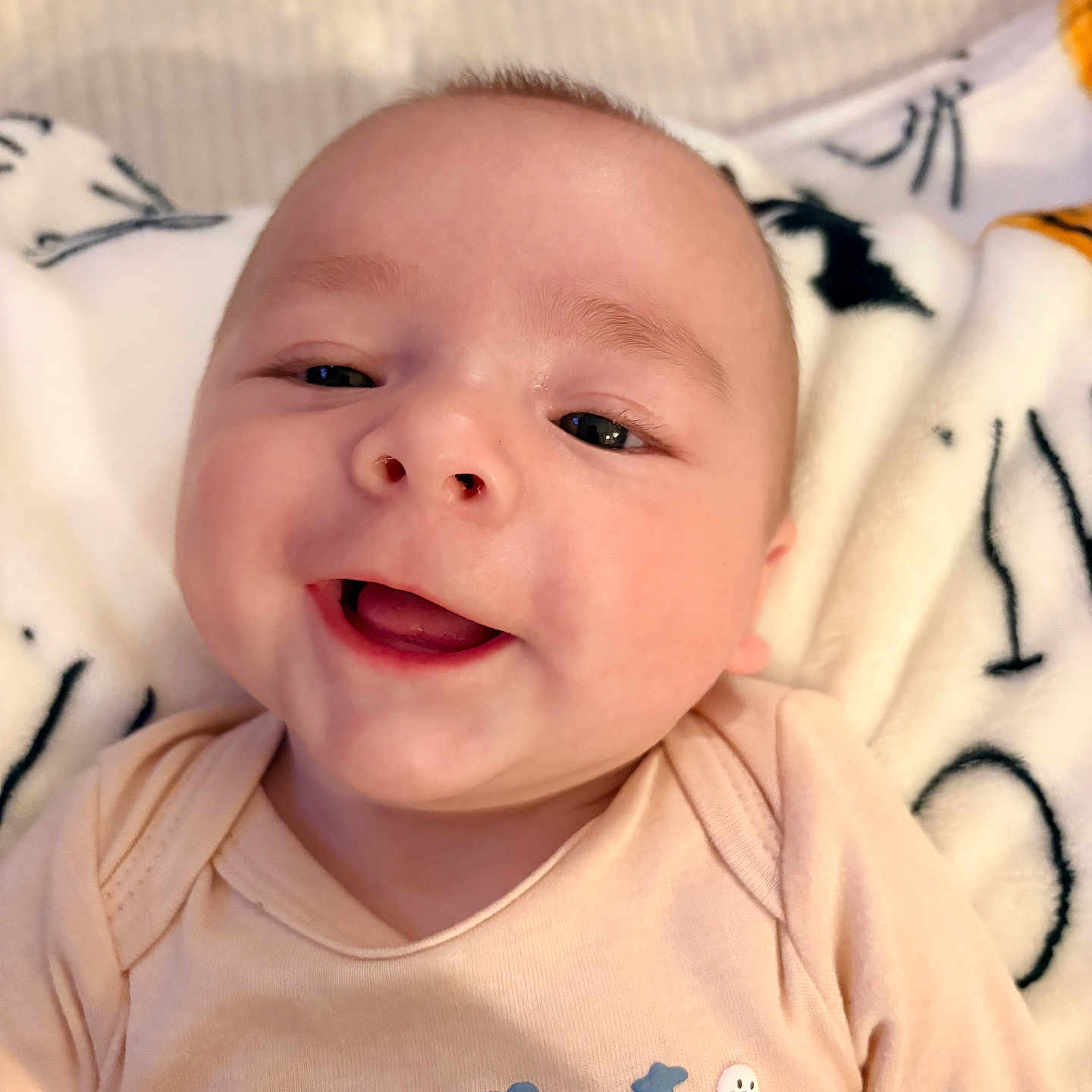 Brooks Bennett joined the competition — help win amazing prizes! baby, blanket, child, clothing, cute, face, halloween, happy, head, holiday, indoor, infant, lying_down, onesie, person, portrait, smiling, soft_texture, text_on_clothing, young