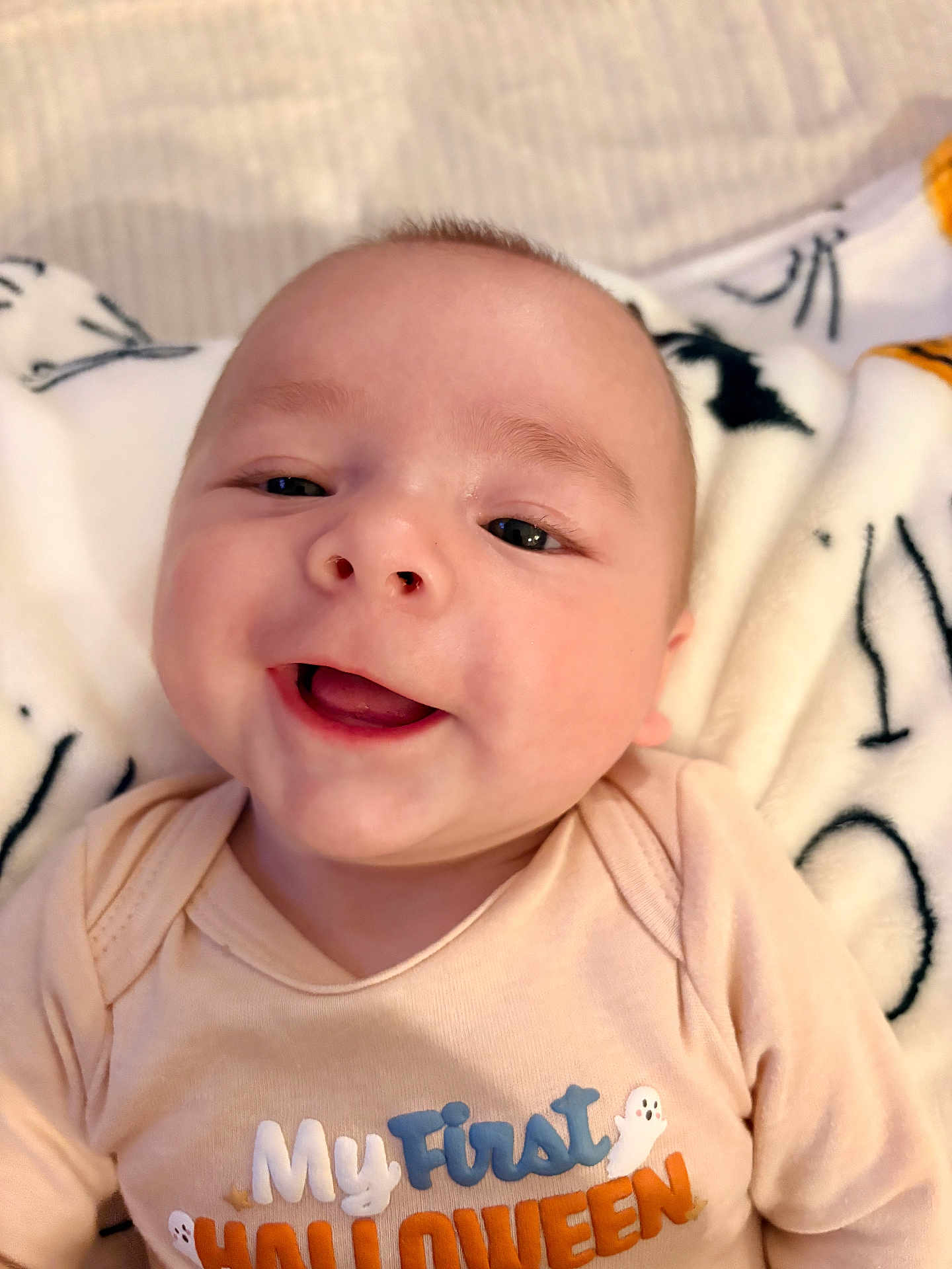 Brooks Bennett joined the competition — help win amazing prizes! baby, infant, smiling, face, clothing, onesie, blanket, cute, happy, child, portrait, lying_down, holiday, halloween, text_on_clothing, indoor, soft_texture, young, person, head