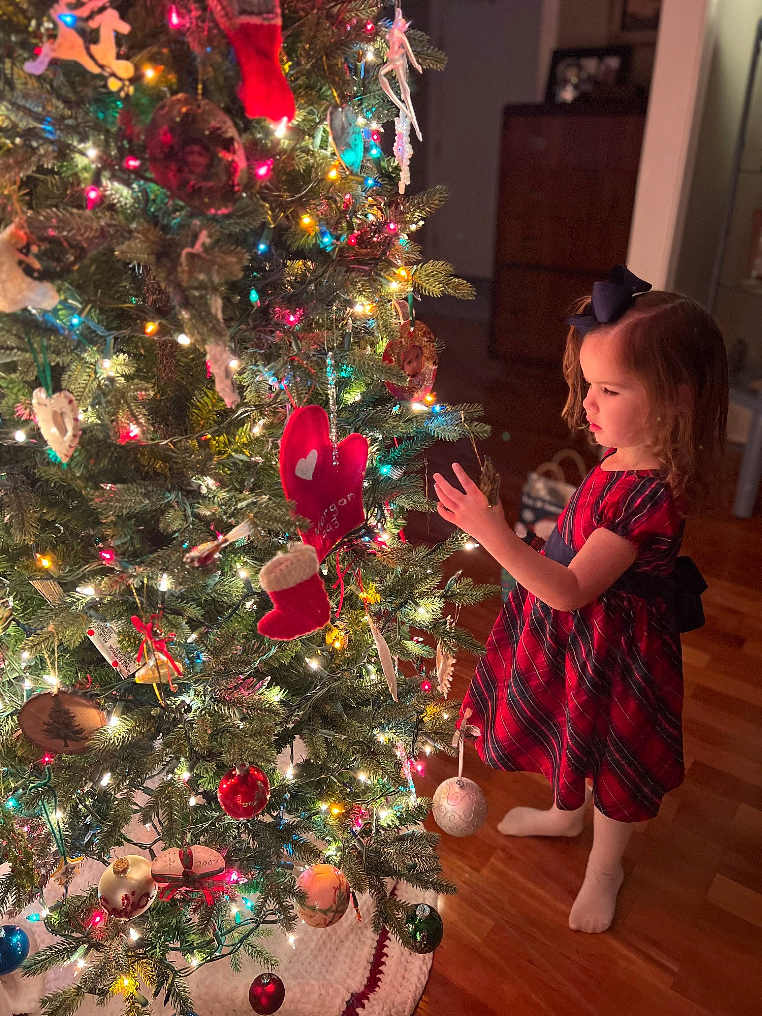 Sofia is registered to the contest to win money with this photo: christmas, christmas_decoration, christmas_eve, christmas_ornament, christmas_tree, conifer, event, evergreen, fun, holiday, holiday_ornament, human_body, interior_design, ornament, person, plant, red, toddler, tradition, tree