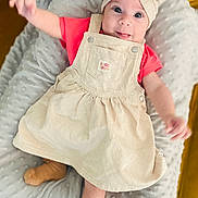 Romy a rejoint le concours — aidez-le/la à gagner de superbes lots ! baby, child, infant, headband, bow, dress, red_shirt, socks, blanket, cushion, smiling, tongue_out, lying_down, soft_texture, indoor, cute, playful, happy, person, closeup