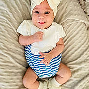 Romy participe au concours pour gagner de l'argent avec cette photo : baby, blanket, blue_and_white, bow, child, closeup, cute, footwear, happy, headband, indoor, infant, lying_down, person, portrait, smiling, socks, soft_texture, striped_clothing, white_clothing