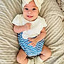 baby, blanket, blue_and_white, bow, child, closeup, cute, footwear, happy, headband, indoor, infant, lying_down, person, portrait, smiling, socks, soft_texture, striped_clothing, white_clothing