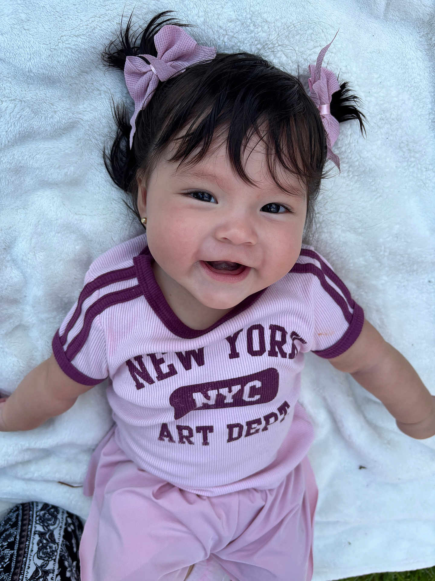Flor De Margarita joined the competition — help win amazing prizes! baby, baby_girl, blanket, child, clothing, cute, face, grass, happy, outdoor, person, pigtails, pink_bows, portrait, shirt, sitting, smile, soft_texture, text, toddler