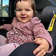 Garance participe au concours pour gagner de l'argent avec cette photo : baby, car_interior, car_seat, child, clothing, cute, face, floral_dress, hair_clip, hand, happy, indoors, infant, person, pink_sweater, portrait, seatbelt, smile, tights, window