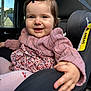 baby, car_interior, car_seat, child, clothing, cute, face, floral_dress, hair_clip, hand, happy, indoors, infant, person, pink_sweater, portrait, seatbelt, smile, tights, window