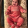 Garance participe au concours pour gagner de l'argent avec cette photo : baby, smiling, infant, pink_clothing, floral_pattern, cushion, happy, face, person, child, soft_texture, lying_down, indoors, cute, small_hands, footed_pajamas, joyful, cheerful, cozy, expression