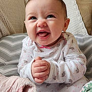 Eleanor is registered to the contest to win money with this photo: baby, smile, clothing, infant, blanket, cushion, happy, indoors, face, person, cute, sitting, pattern, cozy, child, hands, expression, home, cute_outfit, soft