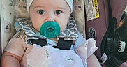 Eleanor is registered to the contest to win money with this photo: baby, pacifier, headband, car_seat, blanket, infant, child, seatbelt, pink, white, floral_pattern, portrait, cute, indoors, child_seat, clothing, baby_girl, soft_toy, sitting, closeup