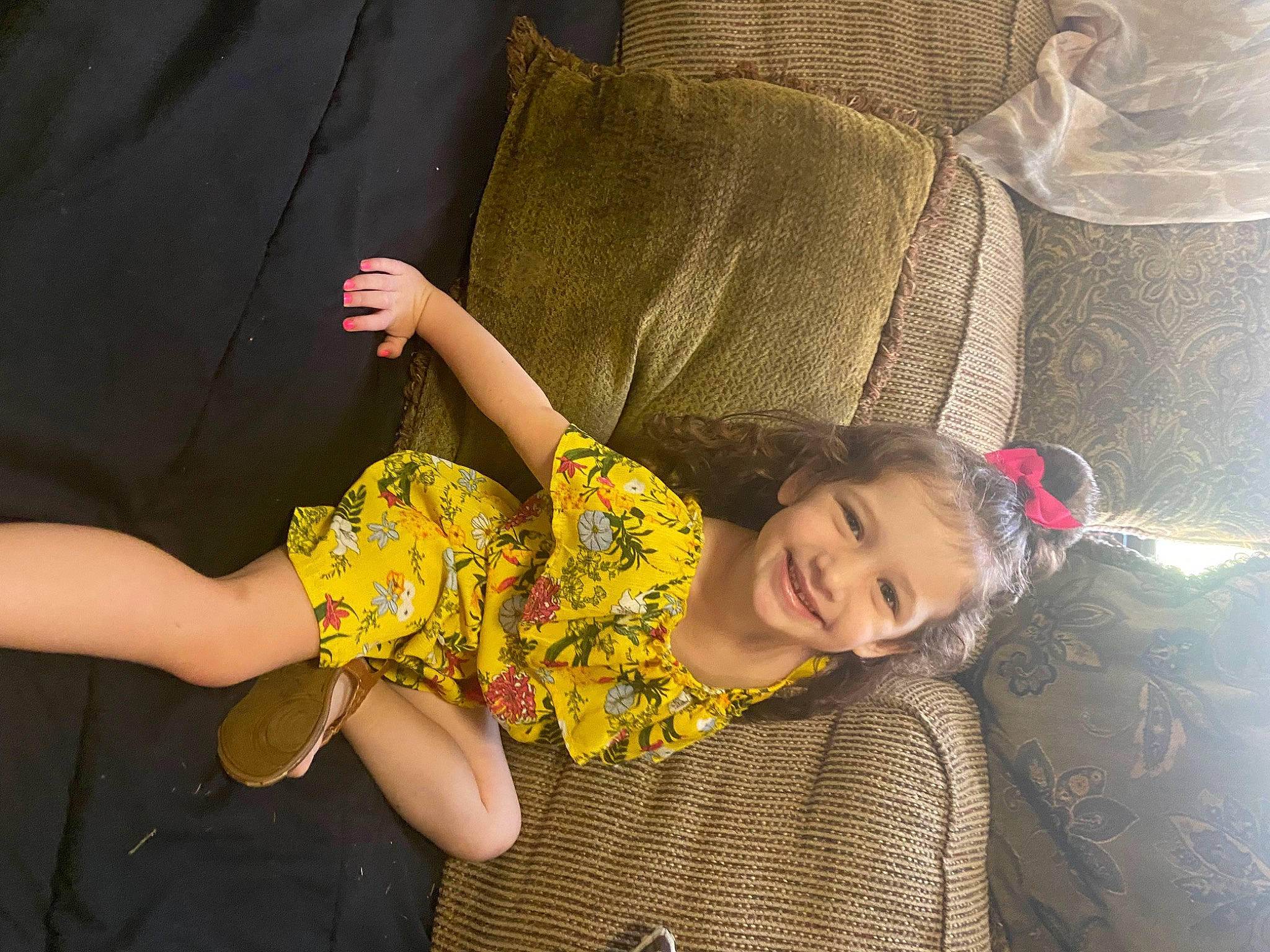Harlow is registered to the contest to win money with this photo: baby_toddler_clothing, beauty, child, comfort, couch, finger, fun, gesture, hand, happy, human_leg, joy, mammal, person, plant, smile, textile, thigh, thumb, toddler