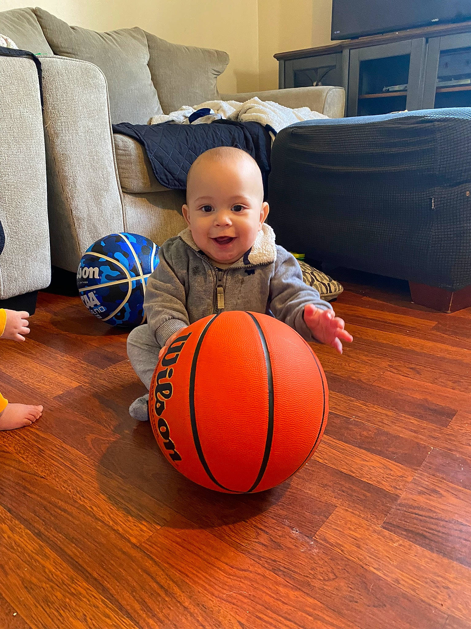 Zakai is registered to the contest to win money with this photo: arm, ball, basketball, comfort, couch, eye, face, floor, flooring, football, hardwood, head, human_body, joy, leg, orange, person, pumpkin, smile, sports_equipment