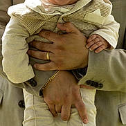 Milán is registered to the contest to win money with this photo: baby, child, smiling, person, adult, holding, outdoor, portrait, clothing, beige, suit, happy, cute, infant, hands, feet, warm, fashion, closeup, family