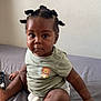Jayce participe au concours pour gagner de l'argent avec cette photo : toddler, child, baby, bantu_knots, hair_style, green_shirt, lion_print, diaper, bed, gray_sheet, remote_control, indoor, wall, curious, serious_expression, dark_skin, sitting, one_person, portrait, casual
