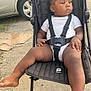 Jayce participe au concours pour gagner de l'argent avec cette photo : toddler, child, stroller, outdoor, car, sidewalk, black_stroller, white_onesie, baby, straps, feet, legs, hand, hair, curly_hair, seat, wheel, daylight, pavement, gaze