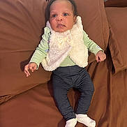 Kierra is registered to the contest to win money with this photo: baby, infant, child, person, clothing, vest, socks, pants, bed, brown_bedspread, lying_down, cute, indoor, young_child, curious, face, hands, feet, sleepwear, portrait