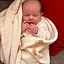 baby, blanket, sleeping, infant, couch, red_cushion, soft_texture, hands, face, peaceful, cozy, wrapped, newborn, cute, portrait, indoors, resting, comfort, warm, relaxation