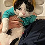 Soup is registered to the contest to win money with this photo: cat, black_and_white, costume, flower_headband, pet, indoor, person_holding_cat, close_up, cute, animal, whiskers, fur, hand, clothing, face, green_eyes, domestic_cat, funny, expression, portrait