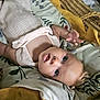 baby, infant, basket, blanket, floral_pattern, mustard_color, sleepwear, lying_down, curious, face, head, skin, hand, indoors, soft_texture, cozy, person, child, newborn, cute