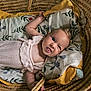 baby, infant, basket, pillow, knitted_outfit, cute, funny_face, tongue_out, expression, woven, fabric, blanket, indoor, child, person, head, skin, comfort, lying_down, soft
