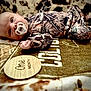 baby, infant, pacifier, camo_clothing, blanket, one_month, lying_down, young_child, face, cute, patterned, soft_texture, newborn, indoor, portrait, child, baby_boy, closeup, floor, resting
