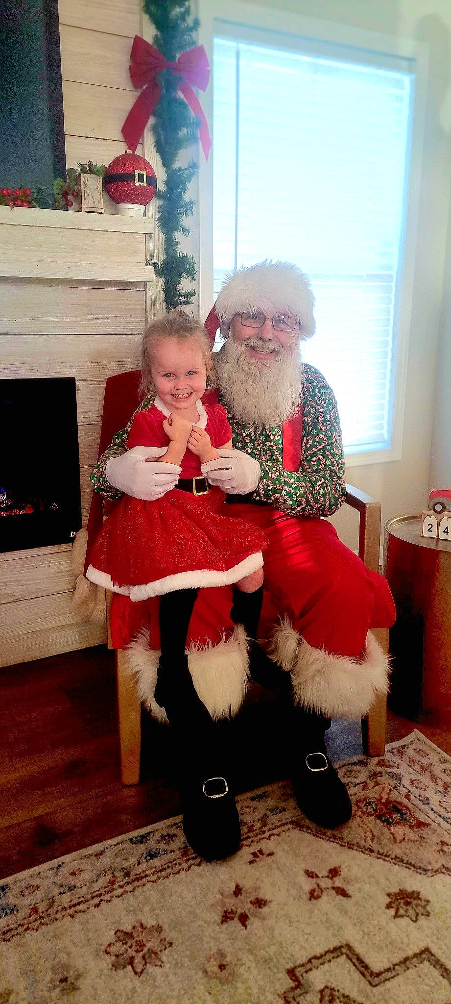 Lily is registered to the contest to win money with this photo: baby, baby_toddler_clothing, beard, child, christmas, event, fictional_character, happy, hardwood, hat, headwear, holiday, human_body, joy, lap, leg, living_room, person, santa_claus, sitting