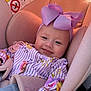 baby, car_seat, purple_bow, smiling, infant, child, striped_clothing, floral_pattern, safety_harness, pink, cute, indoors, seatbelt, headwear, person, child_seat, happy, young_child, pacifier, fabric_texture